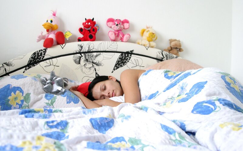 Woman sleeping in bed with stuffed animals