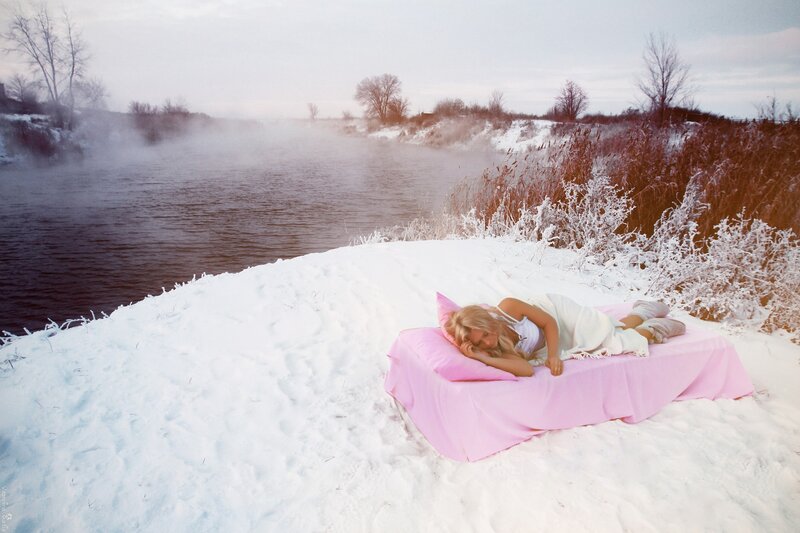 Woman sleeping on pink bed in snow