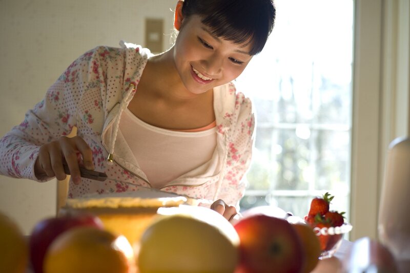 woman slicing cake in kitchen