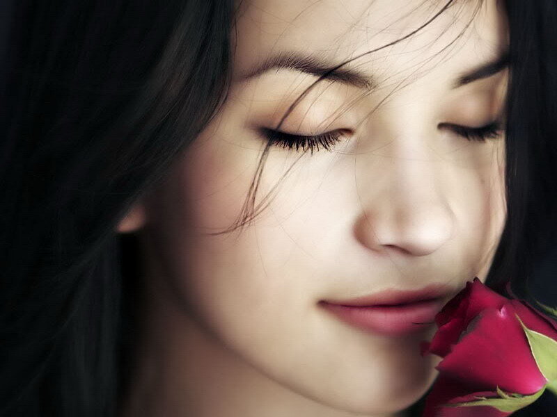 woman smelling a red rose