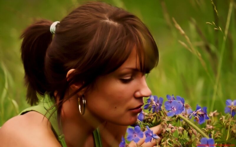 woman smelling blue flowers