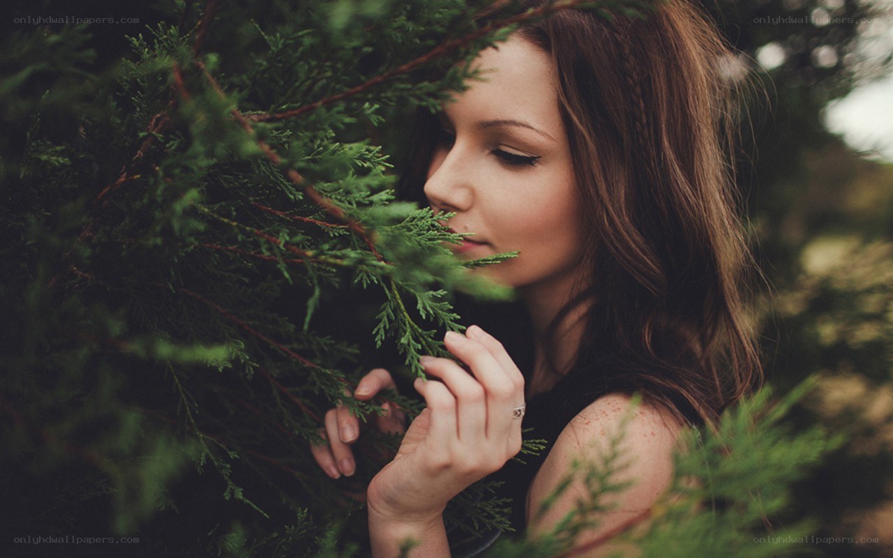 woman smelling evergreen branches