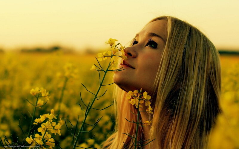woman smelling flowers in field