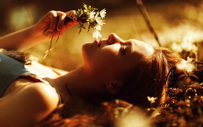 Woman smelling flowers in sunlight