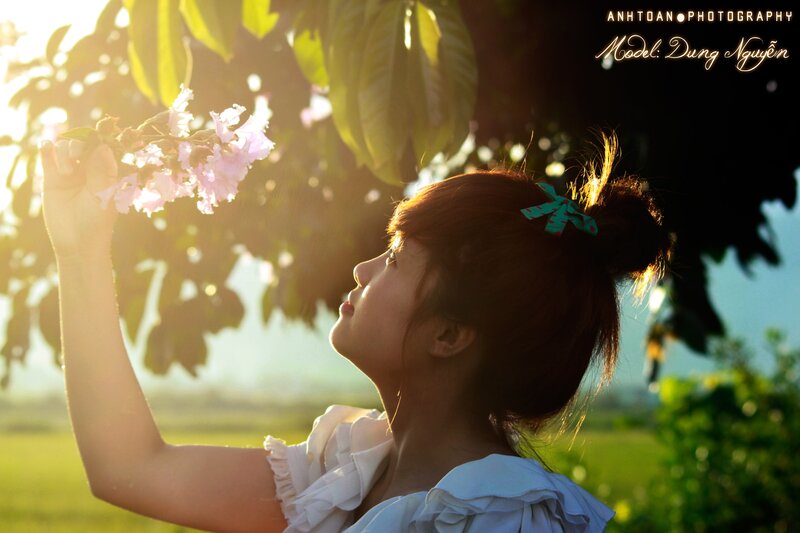 woman smelling flowers in sunlight
