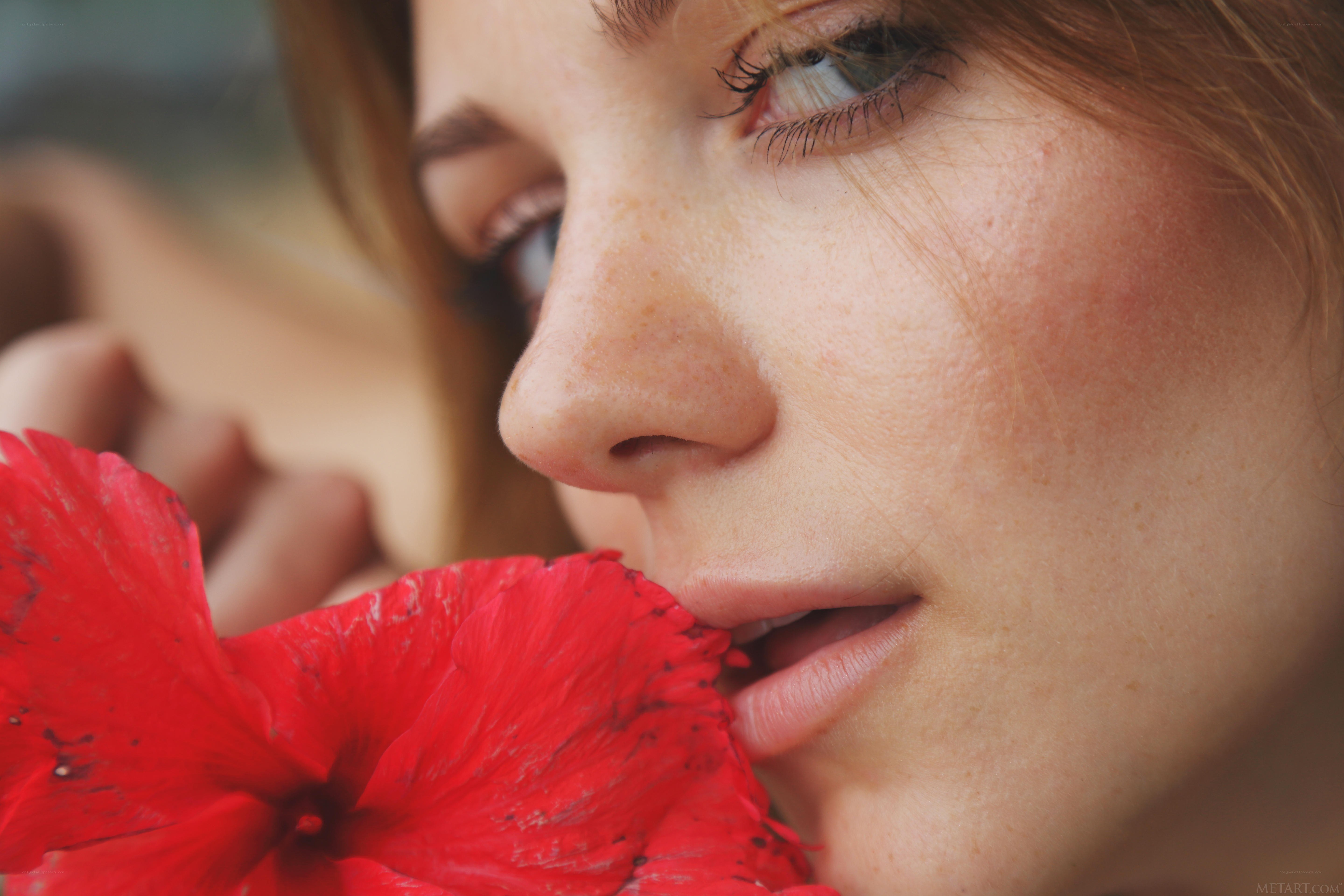 woman smelling red flower