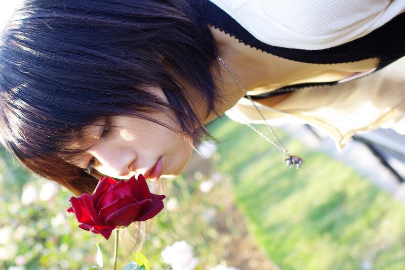 woman smelling red rose