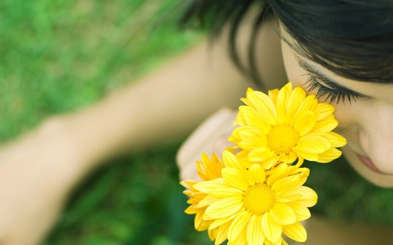 woman smelling yellow flowers