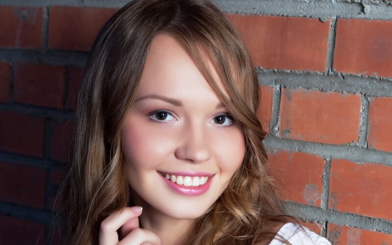 woman smiling against brick wall