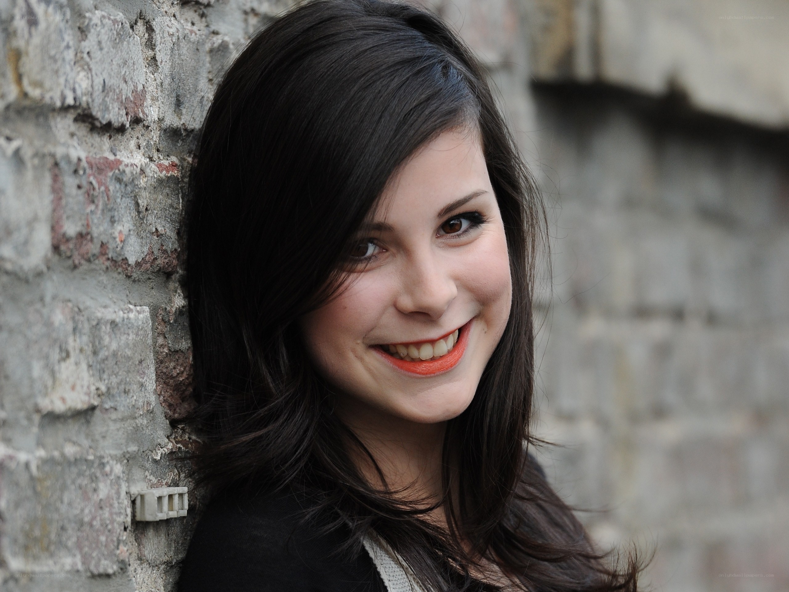 woman smiling against brick wall