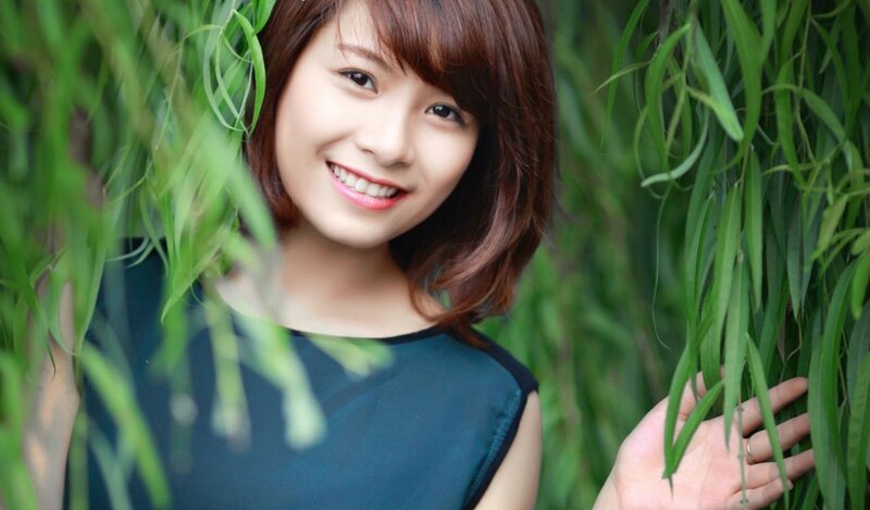 woman smiling among green leaves