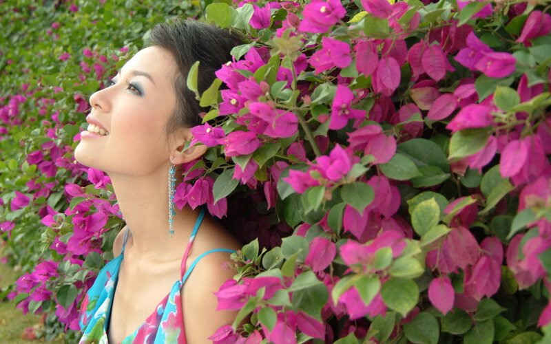 Woman smiling among pink flowers