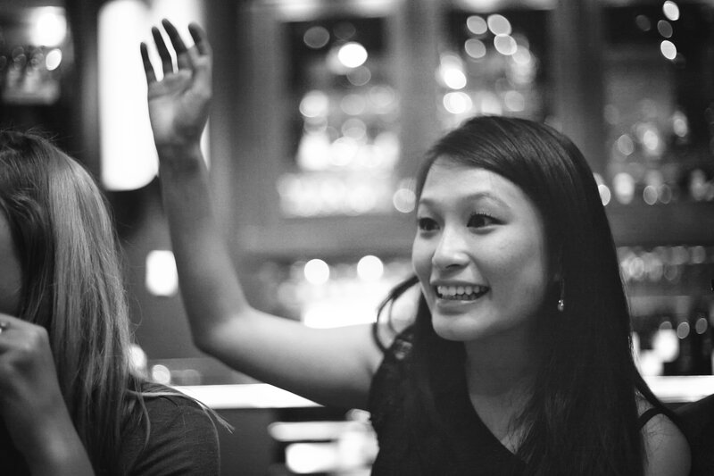 woman smiling and waving at bar