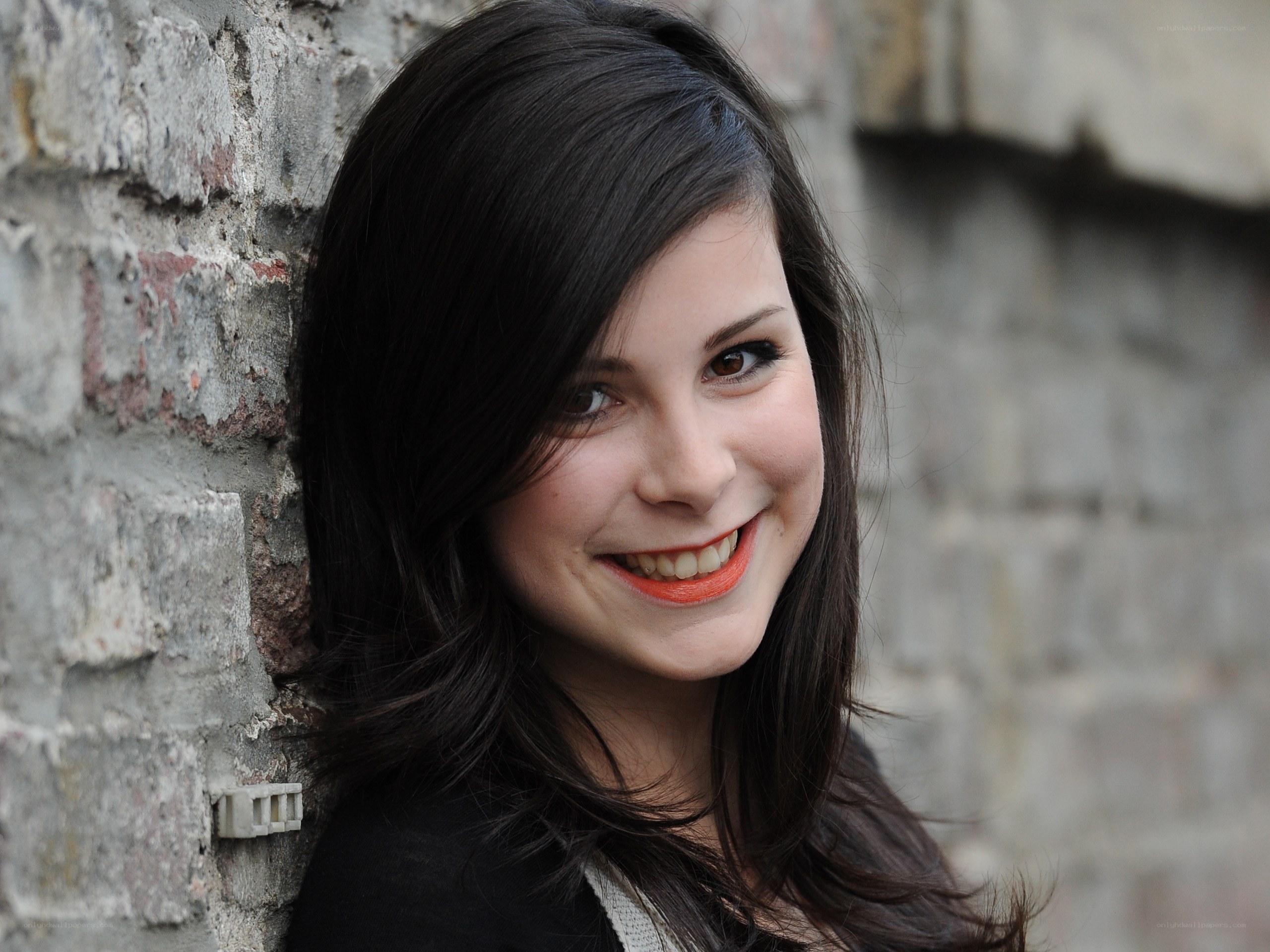 woman smiling by brick wall