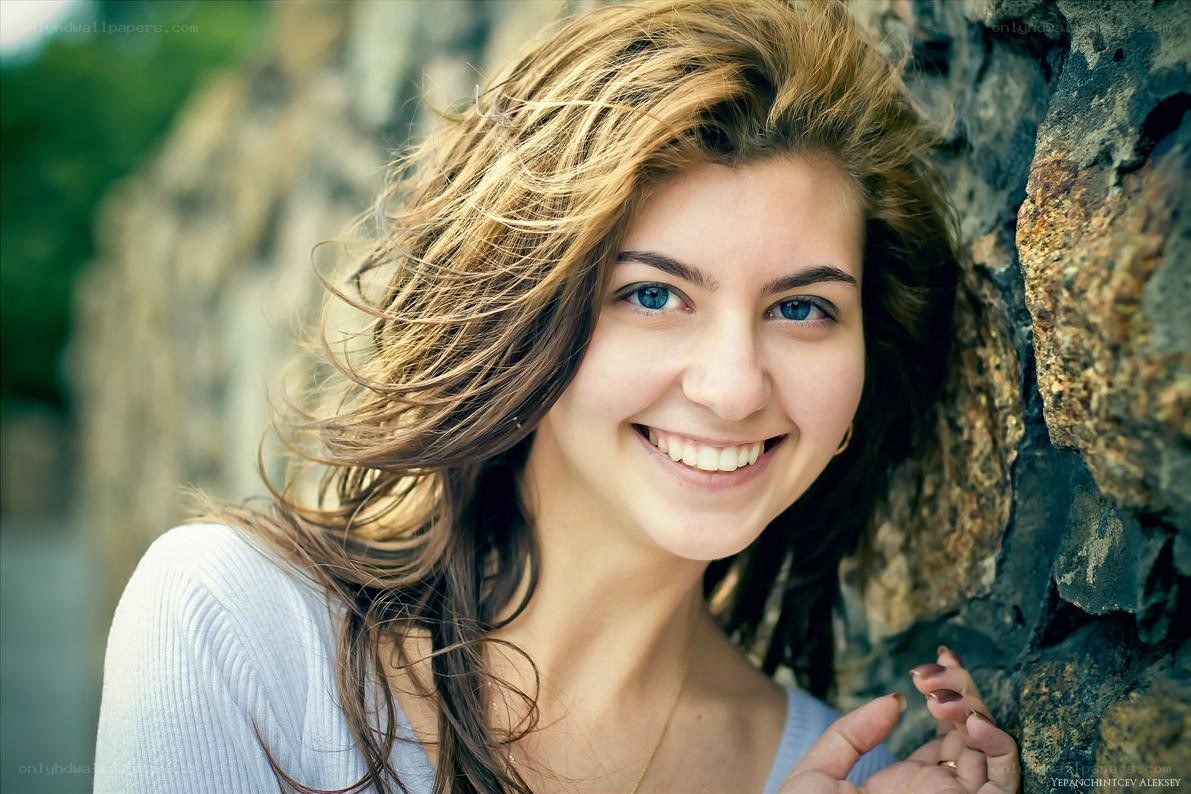 woman smiling by stone wall