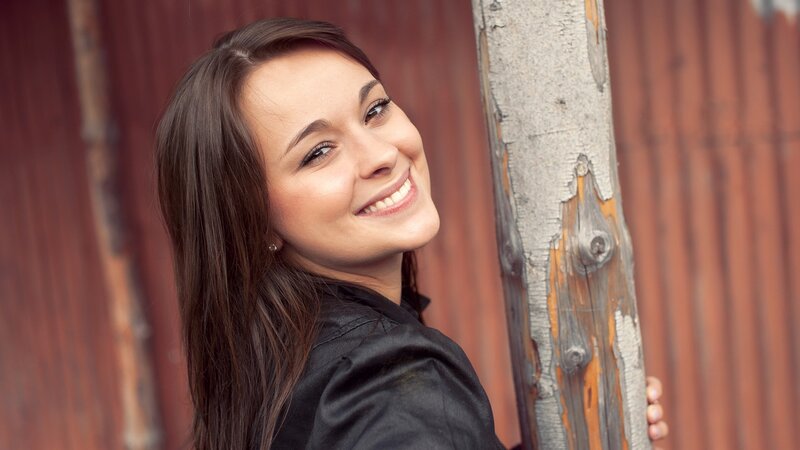 woman smiling by wooden post