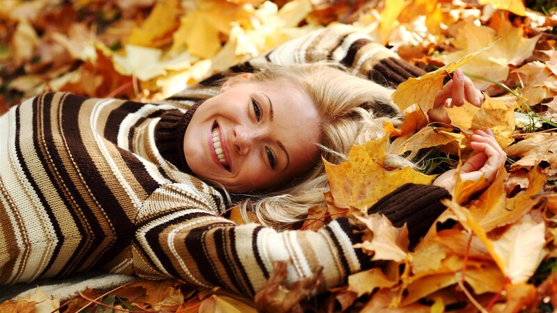 Woman smiling in autumn leaves