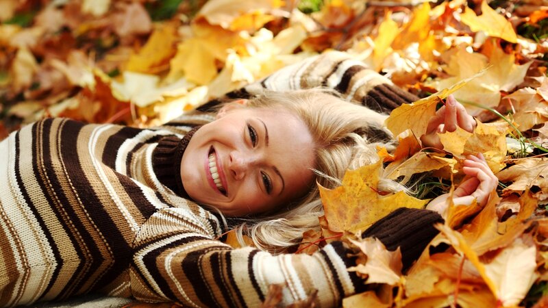 Woman smiling in autumn leaves