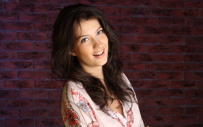 woman smiling in front of brick wall