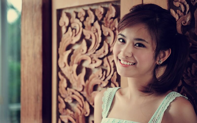 woman smiling in front of carved wood