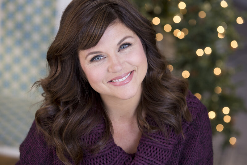 woman smiling in front of christmas tree