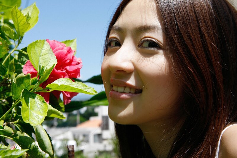 woman smiling near a flower