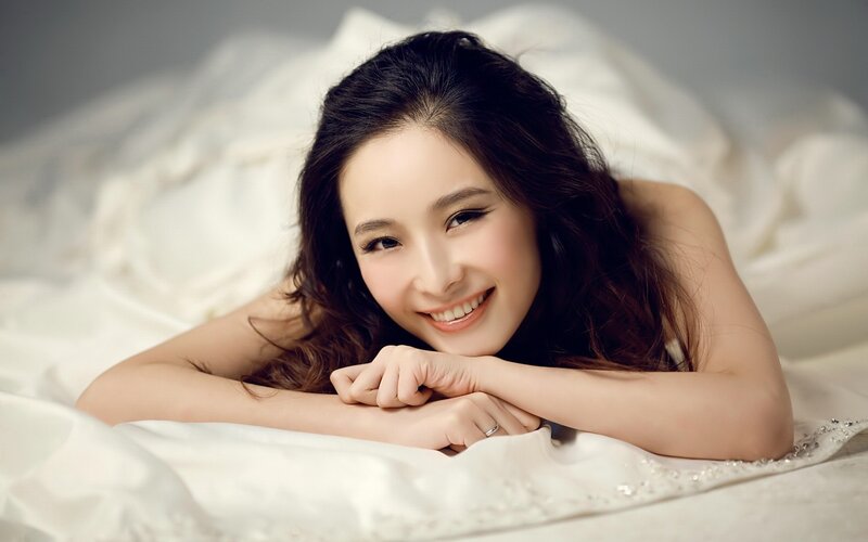 woman smiling on white bed