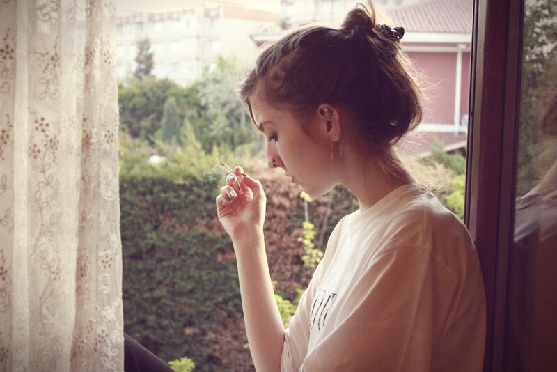 woman smoking by window