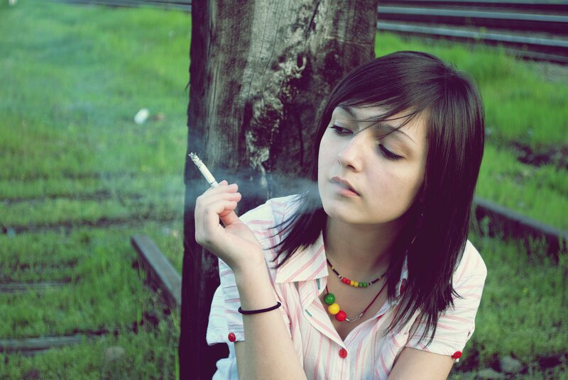 woman smoking near train tracks