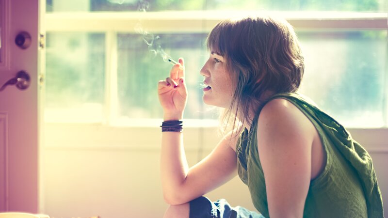 woman smoking near window