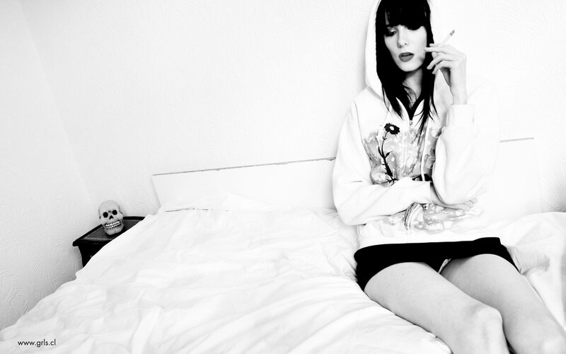 Woman smoking on bed with skull