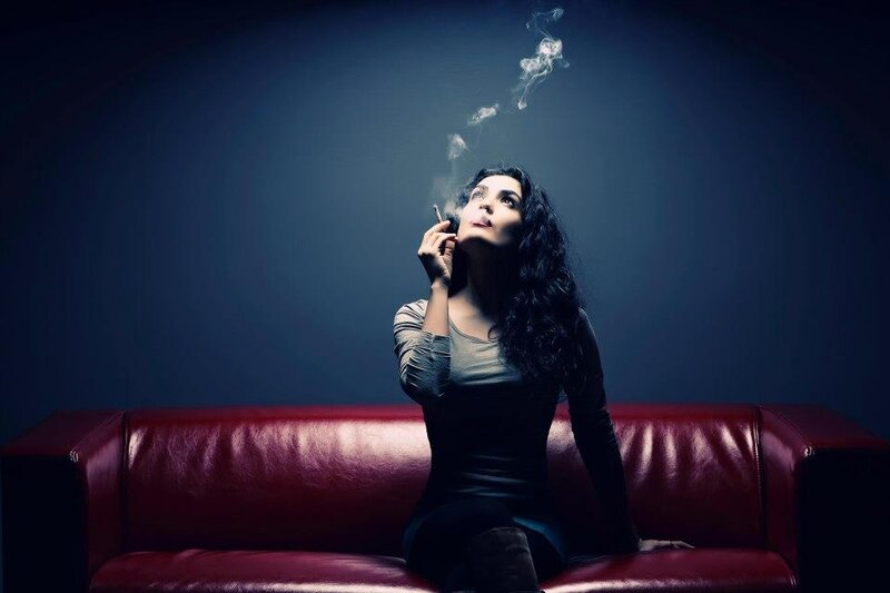woman smoking on red couch