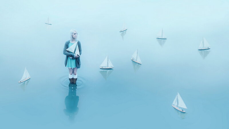 woman standing in water with sailboats