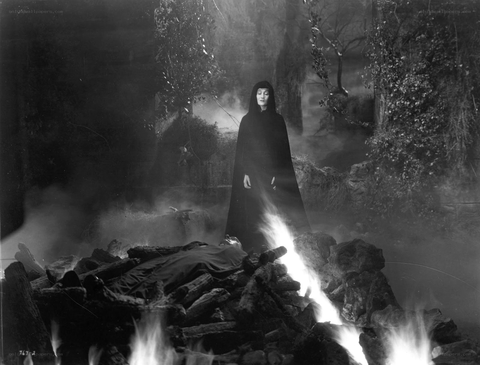 Woman stands over burning pyre