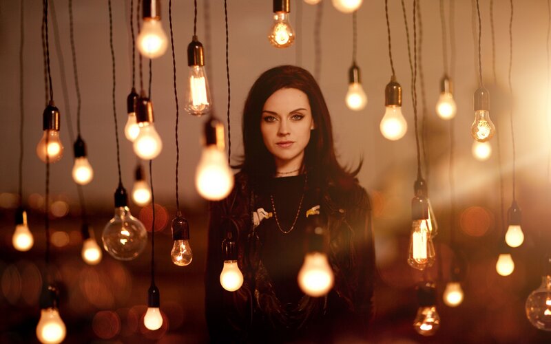woman surrounded by hanging light bulbs