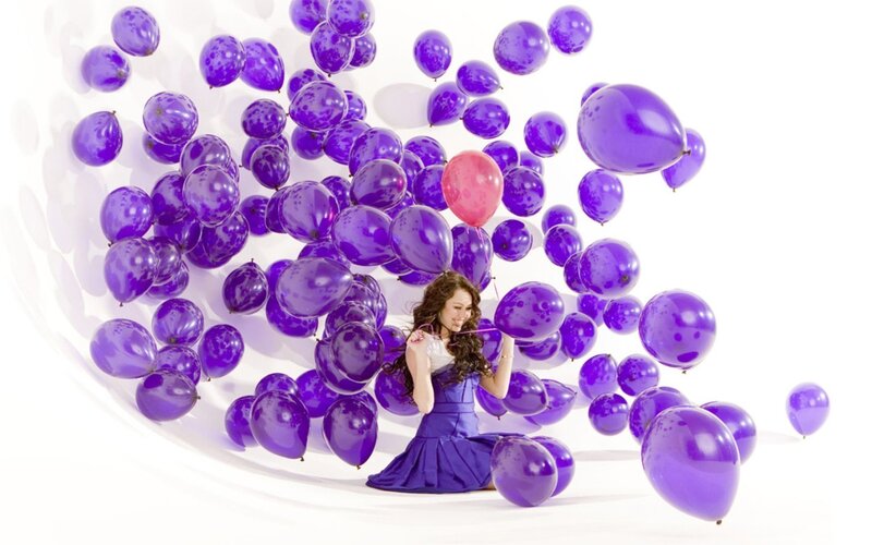 woman surrounded by purple balloons