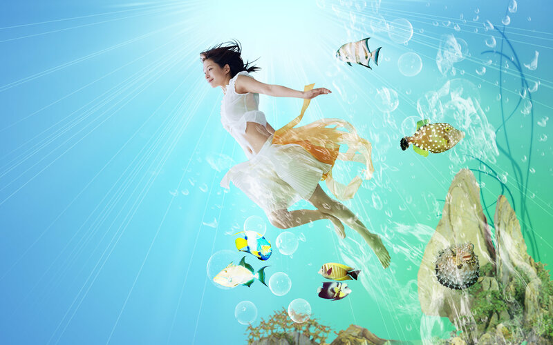 woman swimming underwater with fish