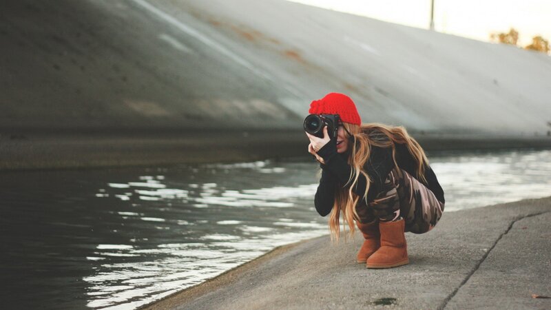 woman taking photo by water