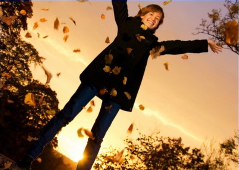 Woman throwing leaves in autumn