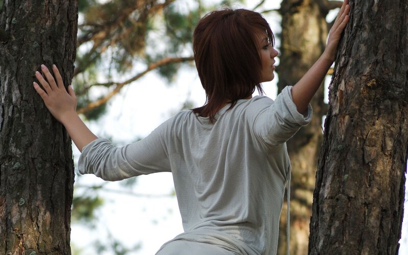 woman touching tree trunks