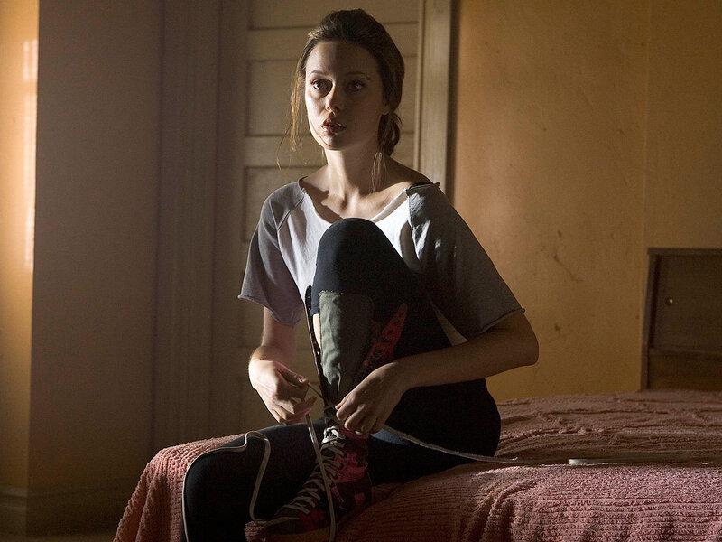 woman tying her shoe on bed