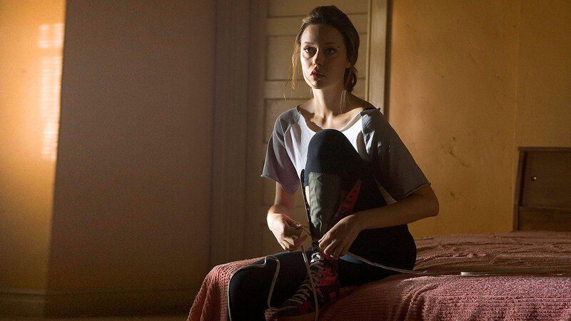 woman tying shoelaces on bed