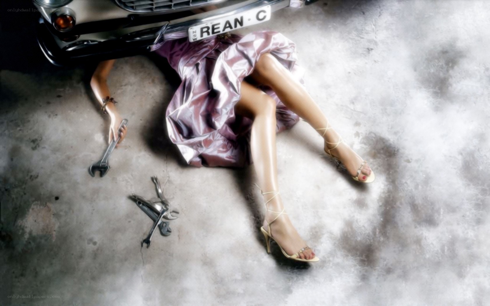 Woman under a car with tools