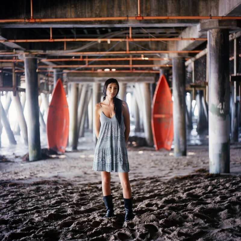Woman under a pier with surfboards