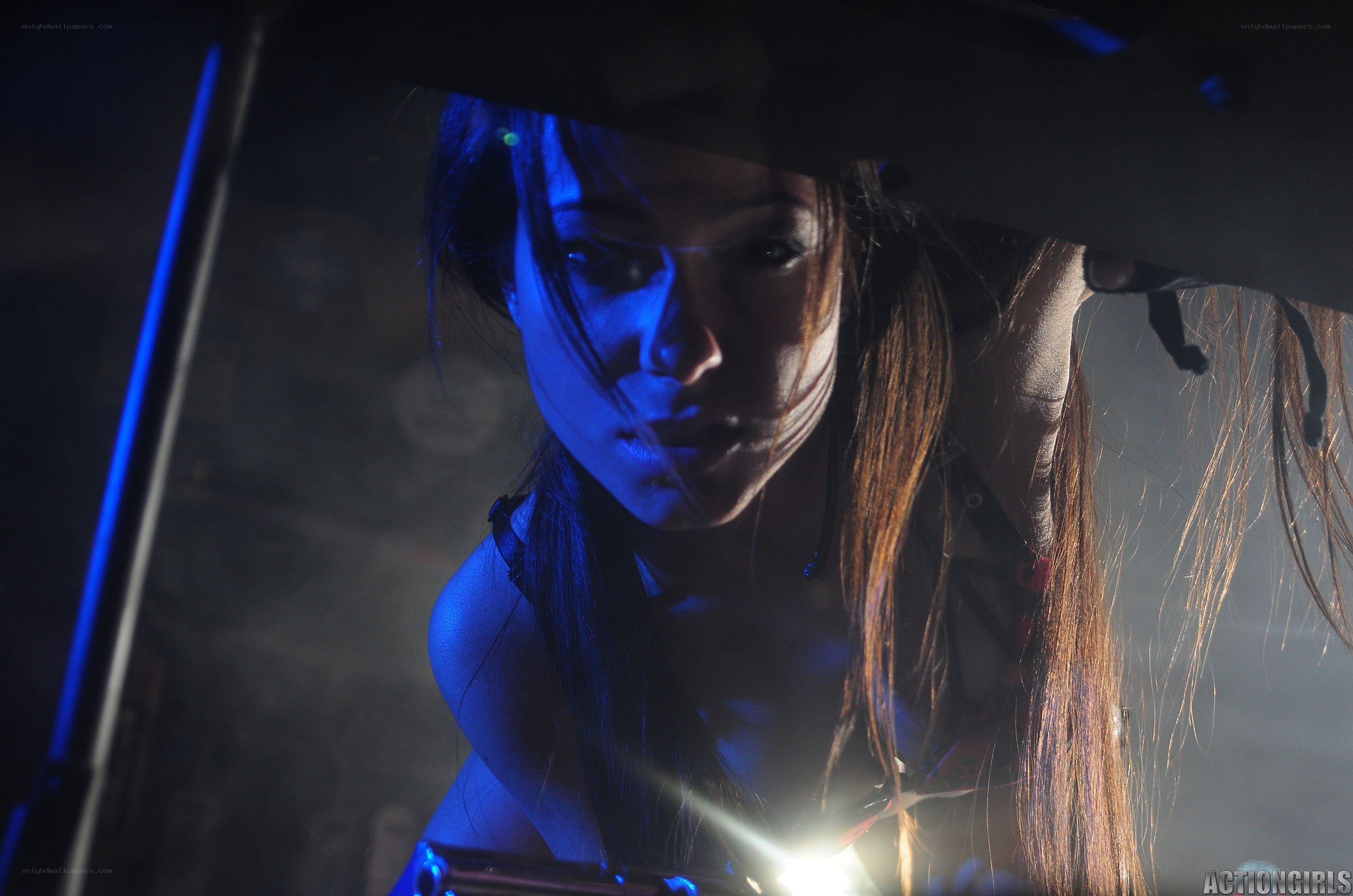 woman under car with flashlight