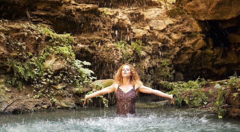 woman under waterfall in cave