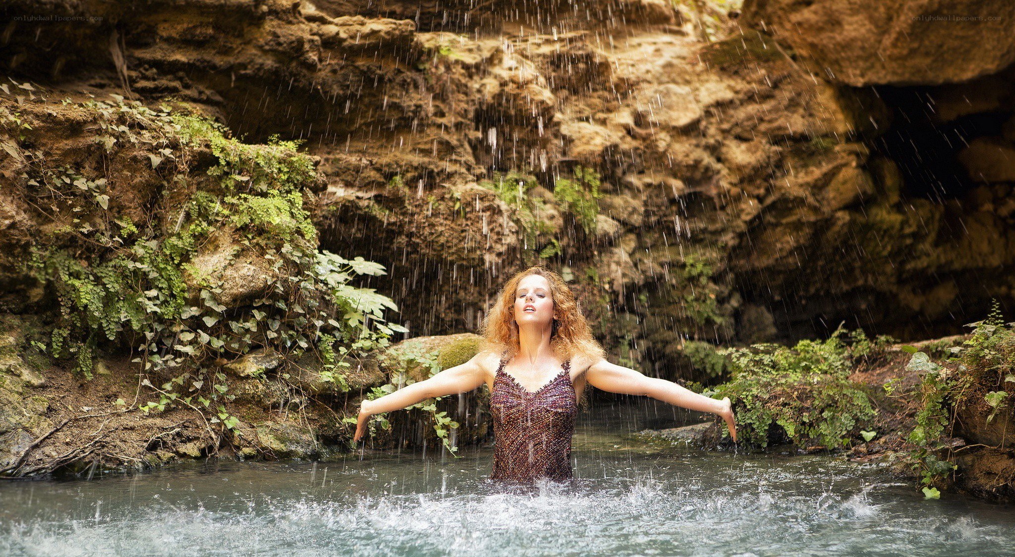 woman under waterfall in cave