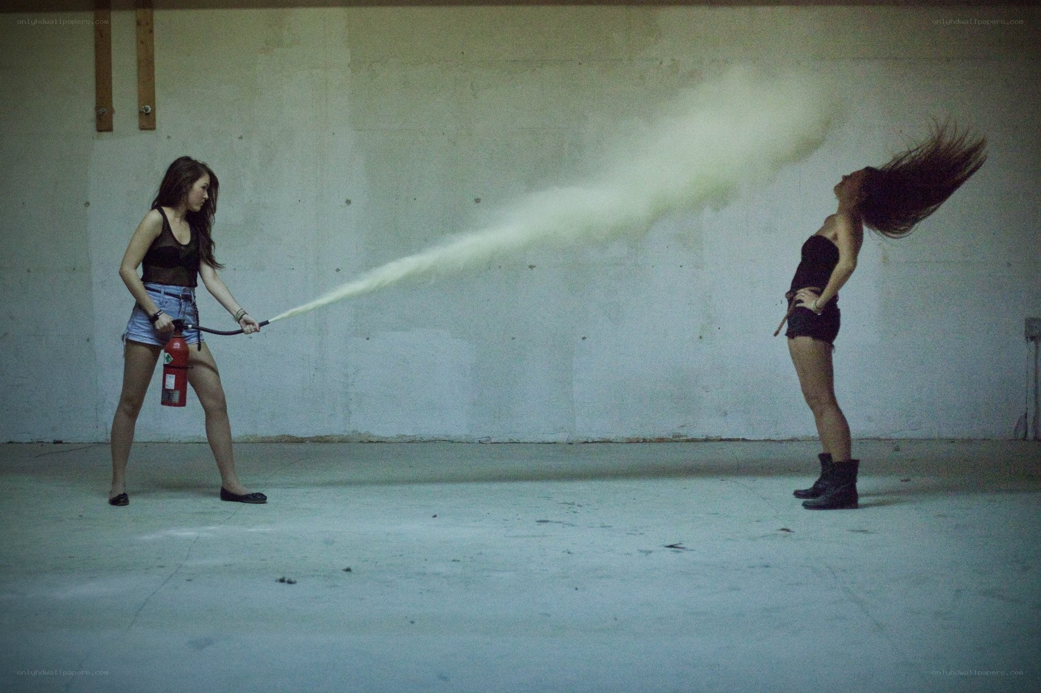 Woman using fire extinguisher on another