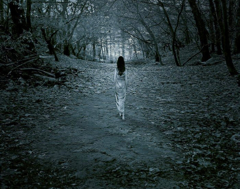Woman walking in a dark forest