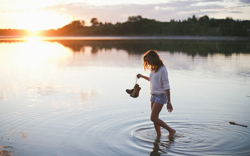woman walking in water at sunset